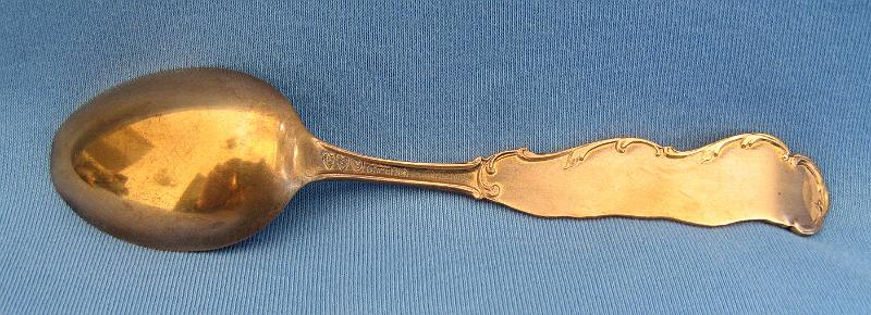 Souvenir Mining Spoon Copper Flat Reverse Side.JPG - SOUVENIR MINING SPOON COPPER FLAT ELY NEVADA - Copper souvenir mining spoon, embossed scene of open pit copper mine in bowl with marking COPPER FLAT at bottom, handle is a skyline depiction of mountains with buildings and smokestacks and a bridge with ELY NEVADA marked on handle, Steptoe Mining and Smelting Co. is marked at the bottom of the skyline, reverse has Paye & Baker makers mark with Sterling x’ed out, 5 1/4 in. long, weight 21 grams [Copper Flat is today a general reference to the area in eastern Nevada where the great copper discoveries were made at the first of the 20th century.  Copper Flat was also small settlement for a short time in this area (now long gone) approximately 6 miles west of Ely, NV in White Pine County.  The Copper Flat area is also associated with several small towns including Kimberly, Riepetown, Ruth and Veteran. The famed open-pit copper mines of eastern Nevada, including the Liberty Pit (largest in the state), are located in this area between Ely and Ruth just south of Highway 50. Through the first half of the 20th century, this area produced nearly a billion dollars in copper, gold and silver. The first mining claims were filed in White Pine County, Nevada, as early as 1867, and the first copper claim was filed in the summer of 1900.  Over the next couple years, an additional 26 claims covering 437 acres of the Copper Flat area were filed.  The Nevada Consolidated Copper Company was organized and incorporated under the laws of Maine on November 17, 1904 to buy up and operate these claims. By May 1906, the company was controlled by the Guggenheim family and their associates and in 1907, steam shovels began stripping the overburden above the Eureka mine to start the open pit mining operations.  In 1906, the Nevada Consolidated Copper Company and the Cumberland and Ely Mining Corporation formed a partnership to build a smelter in the area to process the ores from Copper Flat.  Named the Steptoe Valley Mining and Smelting Company, the smelter started construction in December 1906 at the small town of McGill some 12 miles north of Ely.  The smelter was completed and operations began on May 15, 1908.  The first copper was shipped from the smelter on August 7 of the same year. Kennecott Utah Copper acquired Nevada Consolidated Copper Company, which included Steptoe Valley Mining and Smelting Company and the smelter at McGill, in 1932. In 1983, the price of copper along with the low grade ore being mined led to Kennecott closing the smelter and demolishing it.]